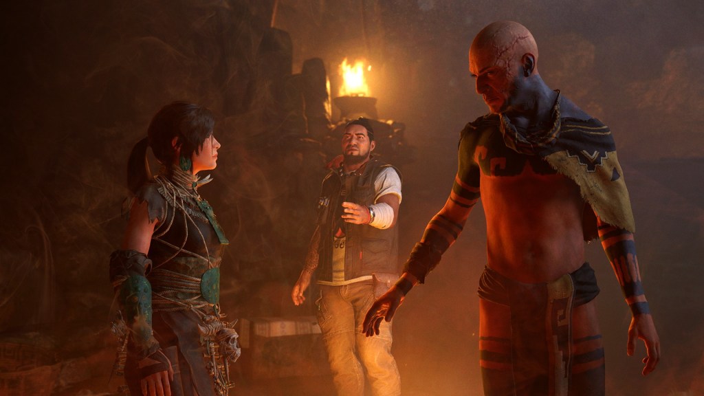 Lara Croft, karanlık bir ortamda iki karakterle karşılıklı etkileşim içinde, bir ateşin ışığının yansıdığı bir sahnede yer alıyor.
