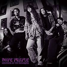 Dope Purple müzik grubunun üyeleri, siyah beyaz bir arka planda oturuyorlar, 1970'ler tarzı giysiler içinde. Grup üyeleri, psychedelik bir rock atmosferini yansıtıyor.